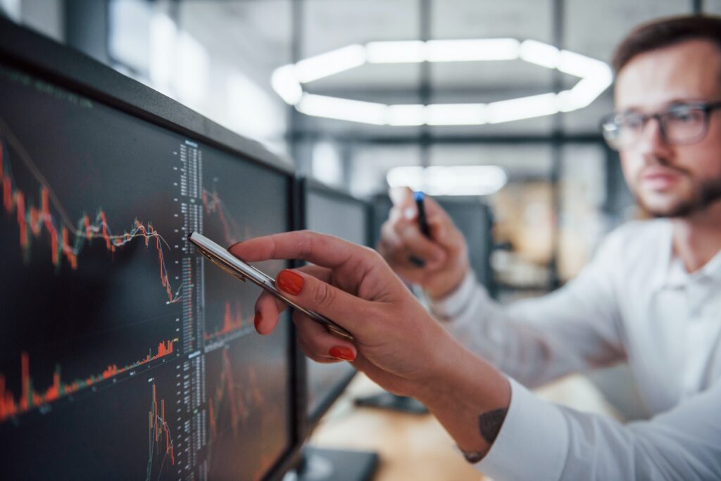 Two stockbrokers in formal clothes works in the office with financial market